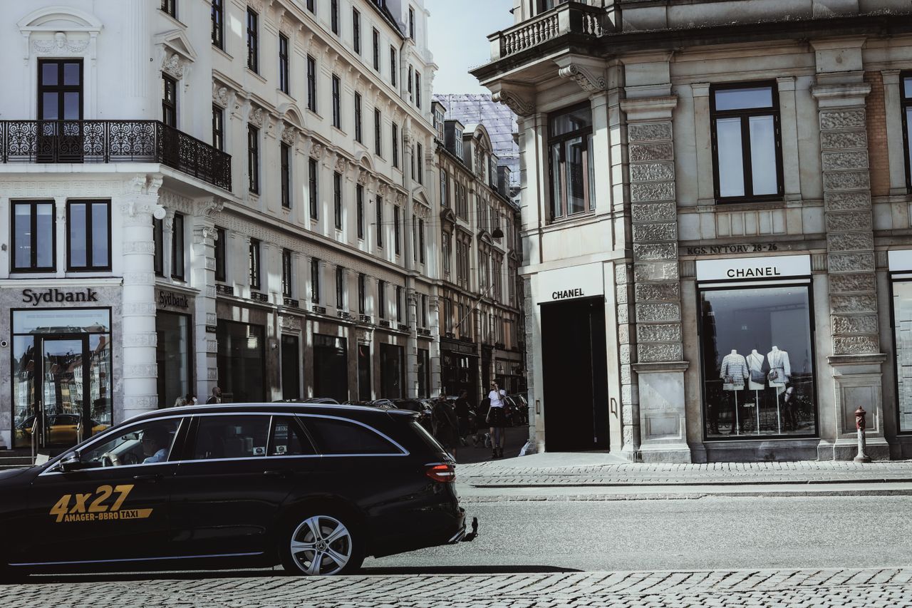 services-02 A bustling street corner in Copenhagen, featuring elegant architecture and a Chanel storefront.