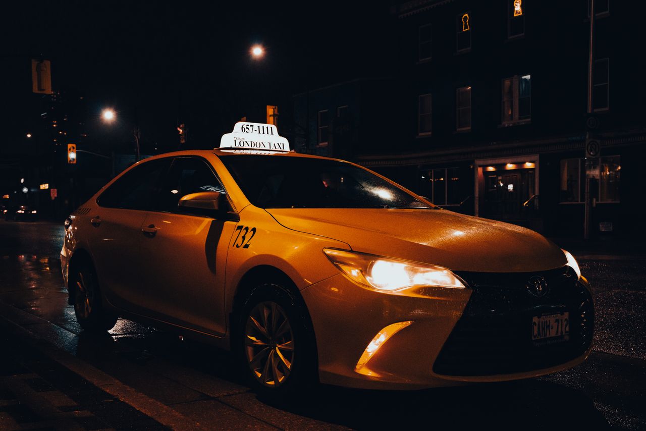 gallery-1 A yellow taxi waiting at night in London, Ontario, Canada. Urban transportation captured with street lights.