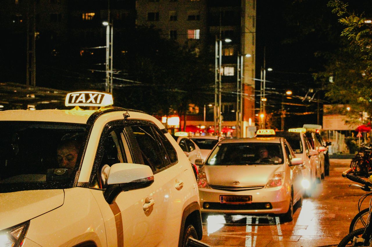 why-choose-us Taxis lined up under streetlights in Salzburg, Austria, captured at night.