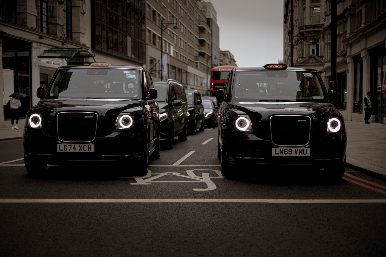 gallery-2 Black taxis line up on a London street showcasing modern urban transportation.